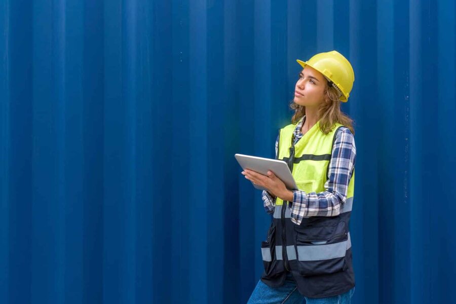 Image of a woman in a hard hat standing in front of a storage container